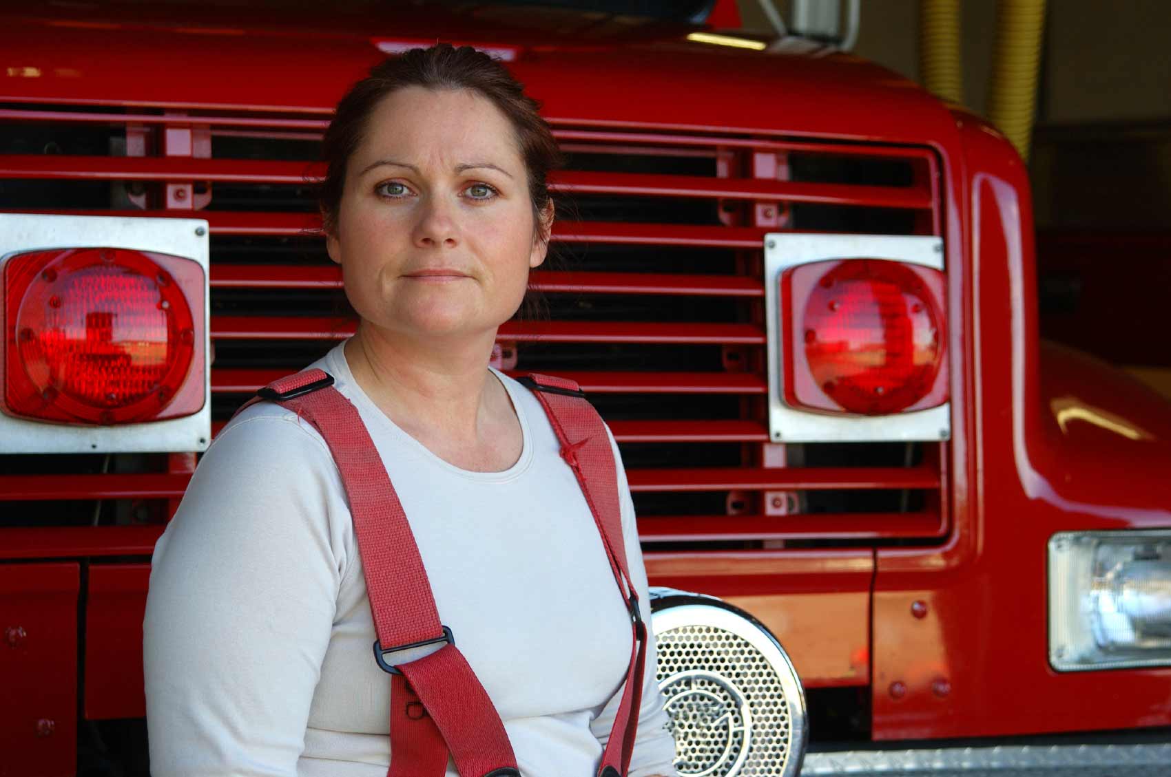 Women firefighter standing in front of fire truck.